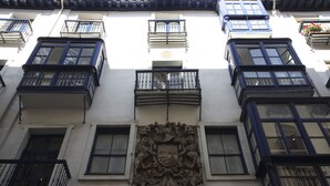 Fachada de edificio con múltiples ventanas, balcones y un escudo central.