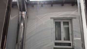 Un estrecho callejón con una ventana y una tubería de metal.