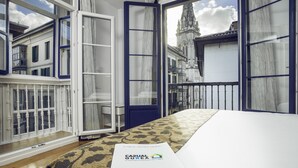 Habitación de hotel con vista a un edificio histórico, un tapete estampado y un folleto sobre la cama.