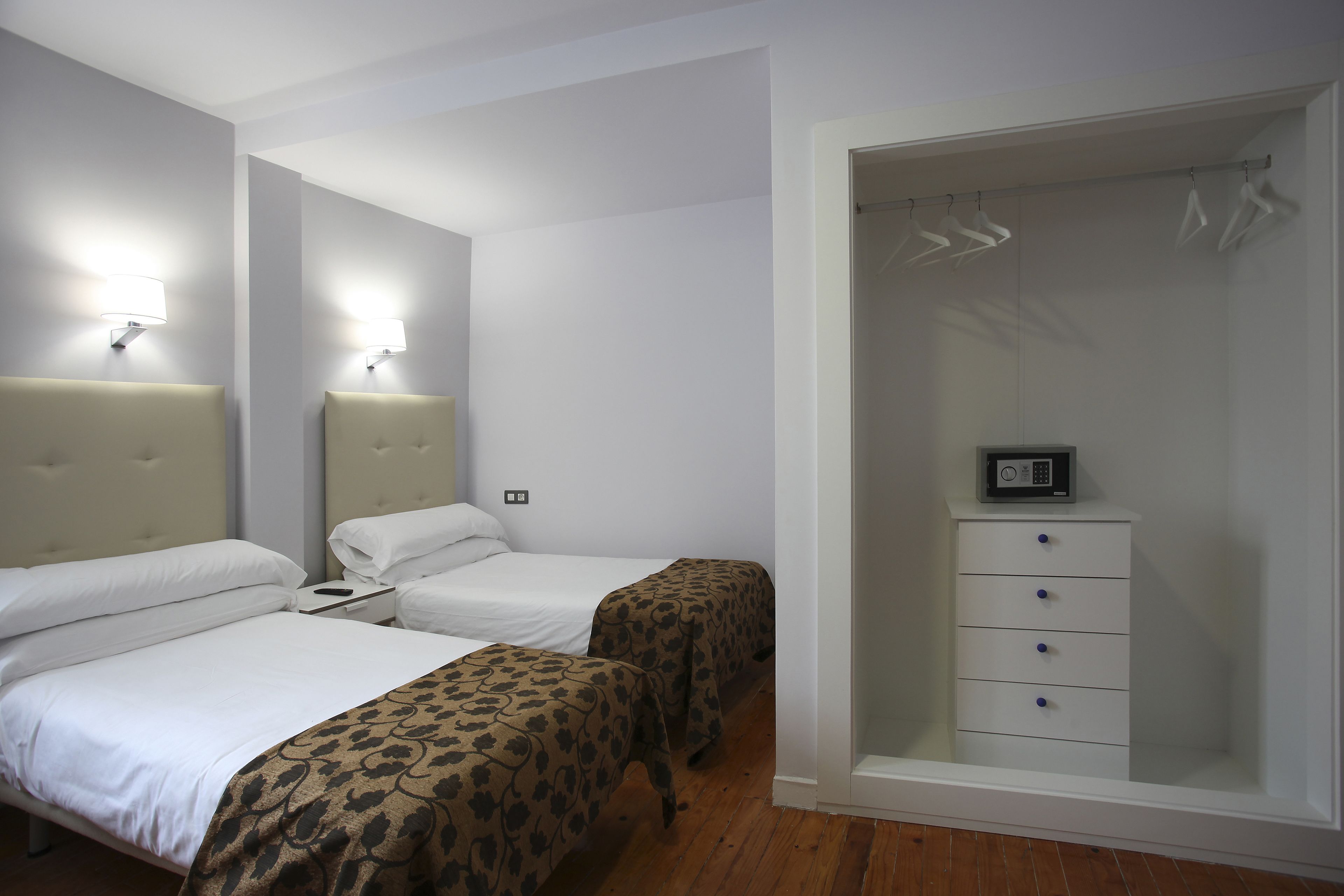 Una habitación de hotel con dos camas, un armario y una mesita de noche.