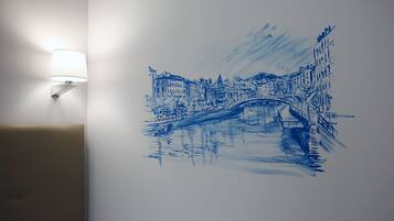 Paret amb un dibuix blau d'un pont i edificis, i una làmpada penjada a la paret.