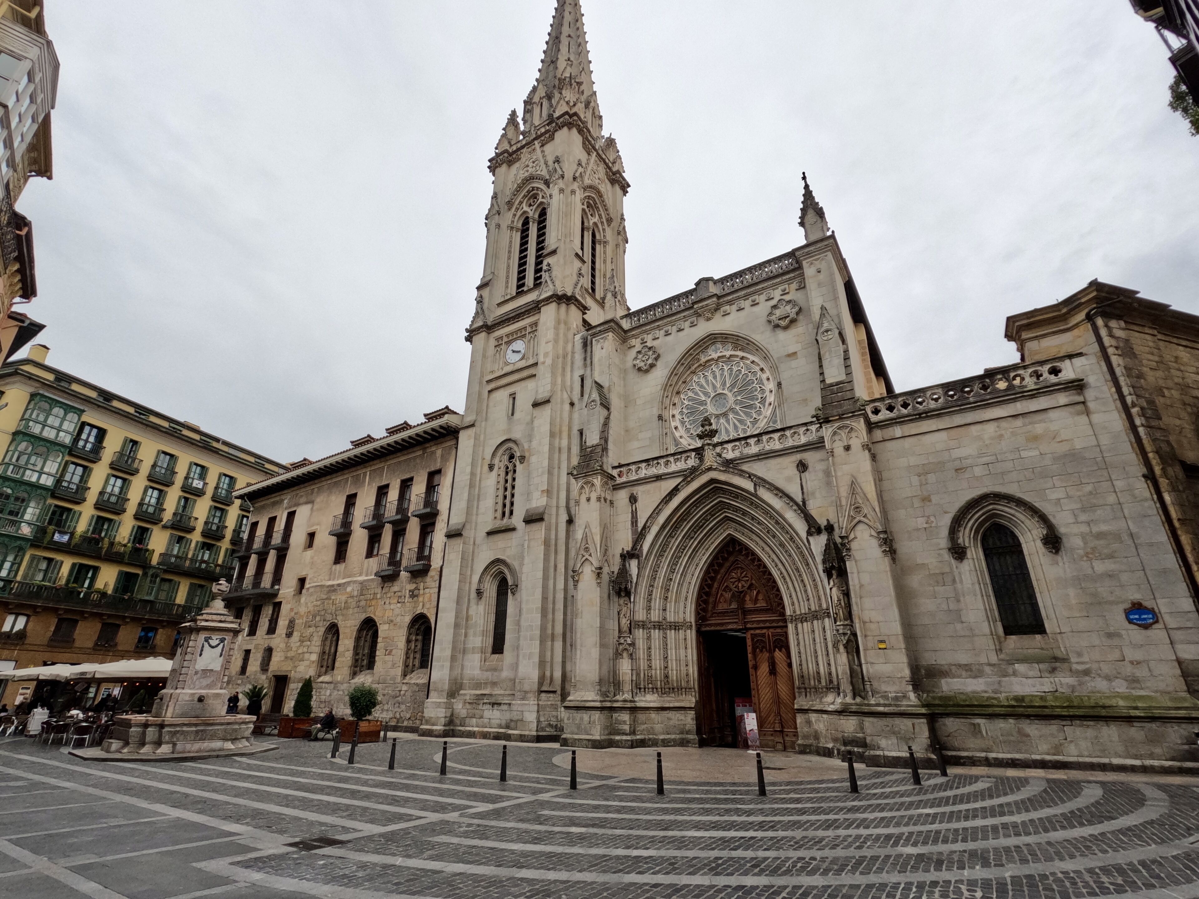 A historic church with a tall spire and a large circular stained glass window.