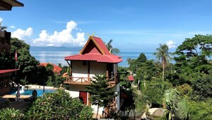 A resort with a pool, a red-roofed building, and a view of the ocean. - Moonstone Studio (Ko Pha-ngan)