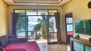 A room with a bed, a TV, and a view of the sea. - Moonstone Studio (Ko Pha-ngan)