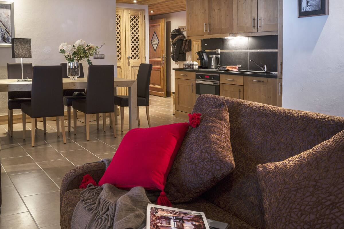 A living room with a sofa, a magazine, and a dining area with chairs and a table.