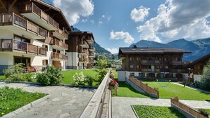 A mountain resort with multi-story buildings, stone pathways, and well-maintained gardens. - CGH Résidences & Spas Les Chalets d'Angèle (Chatel)