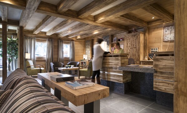 A cozy cabin interior with wooden beams, a dining area with books, and a bar area with a clock.