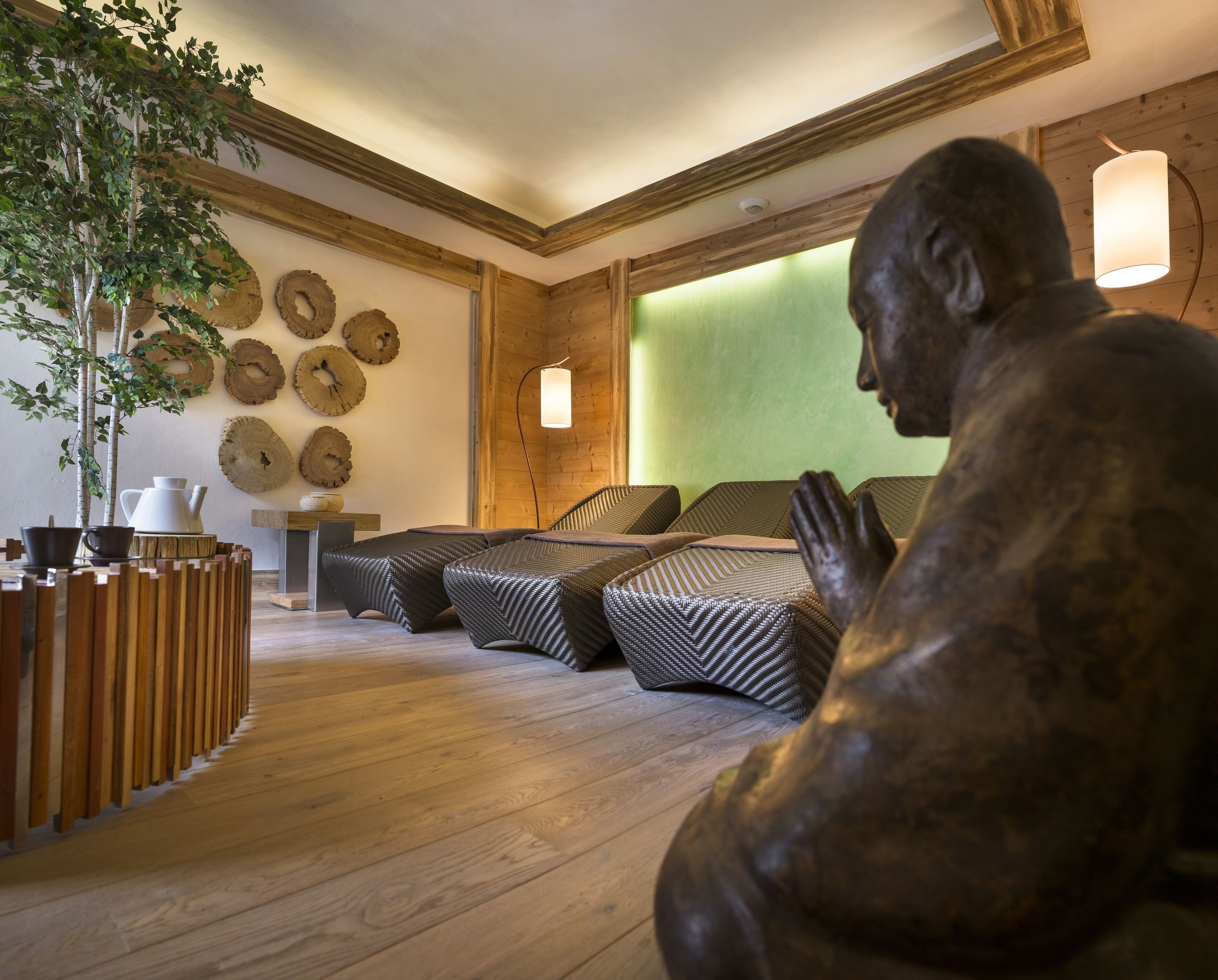 A room with a wooden floor, a statue, a green wall, and a ceiling with wooden beams.