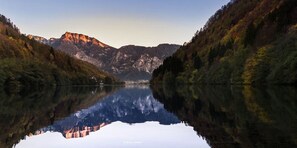 A calm lake reflecting mountains and trees. - Hotel Ariston (Levico Terme)