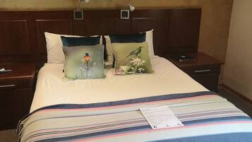 A hotel room with a bed, two nightstands, a wooden headboard, and three wall-mounted paintings of birds.