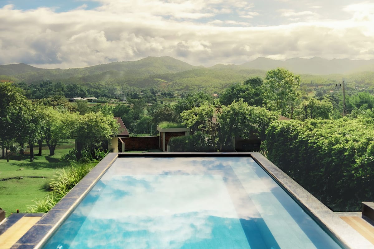 A swimming pool with a view of a mountainous landscape and lush greenery.