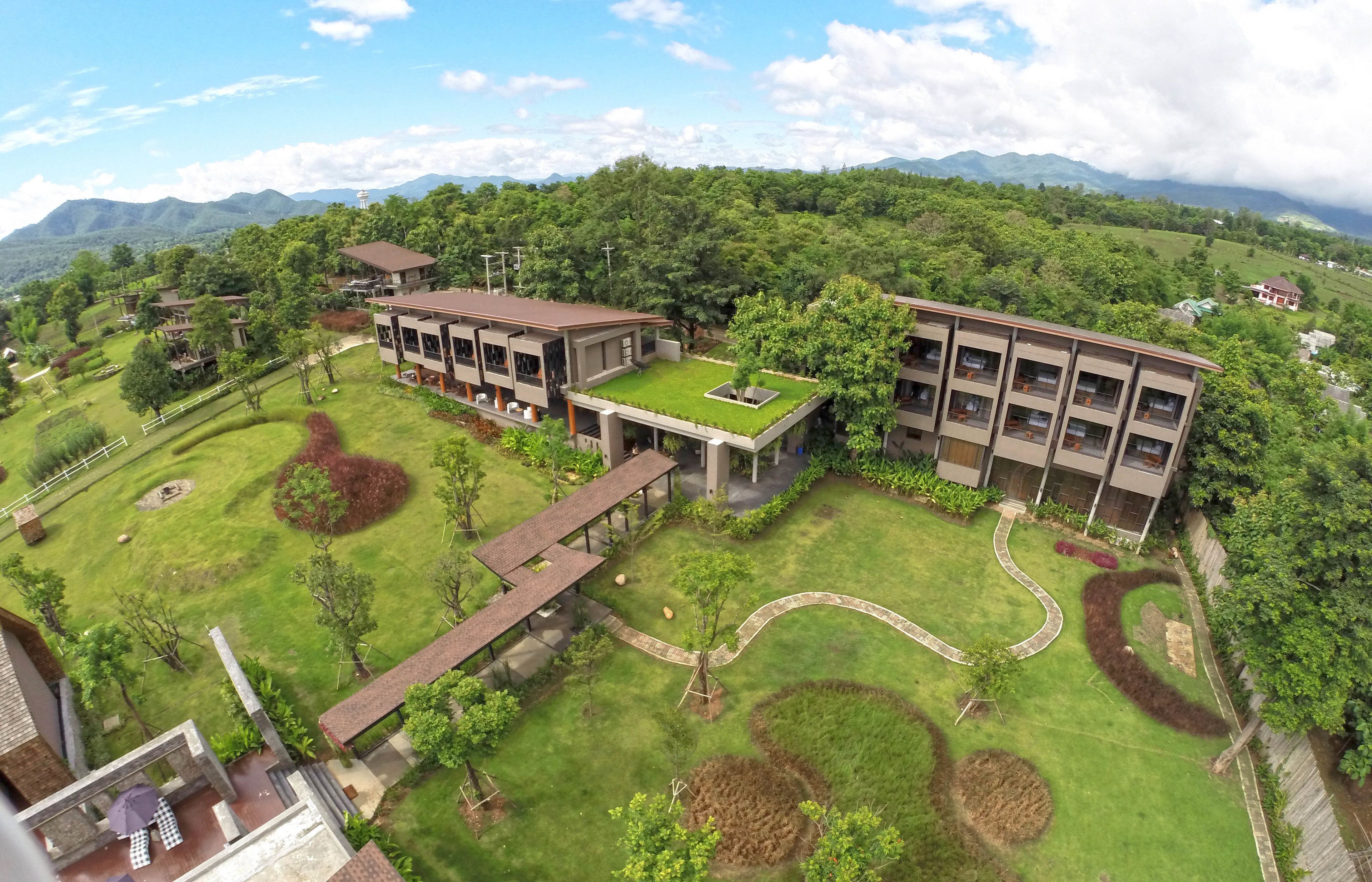 A modern building with a flat roof garden, surrounded by well-maintained lawns and trees.