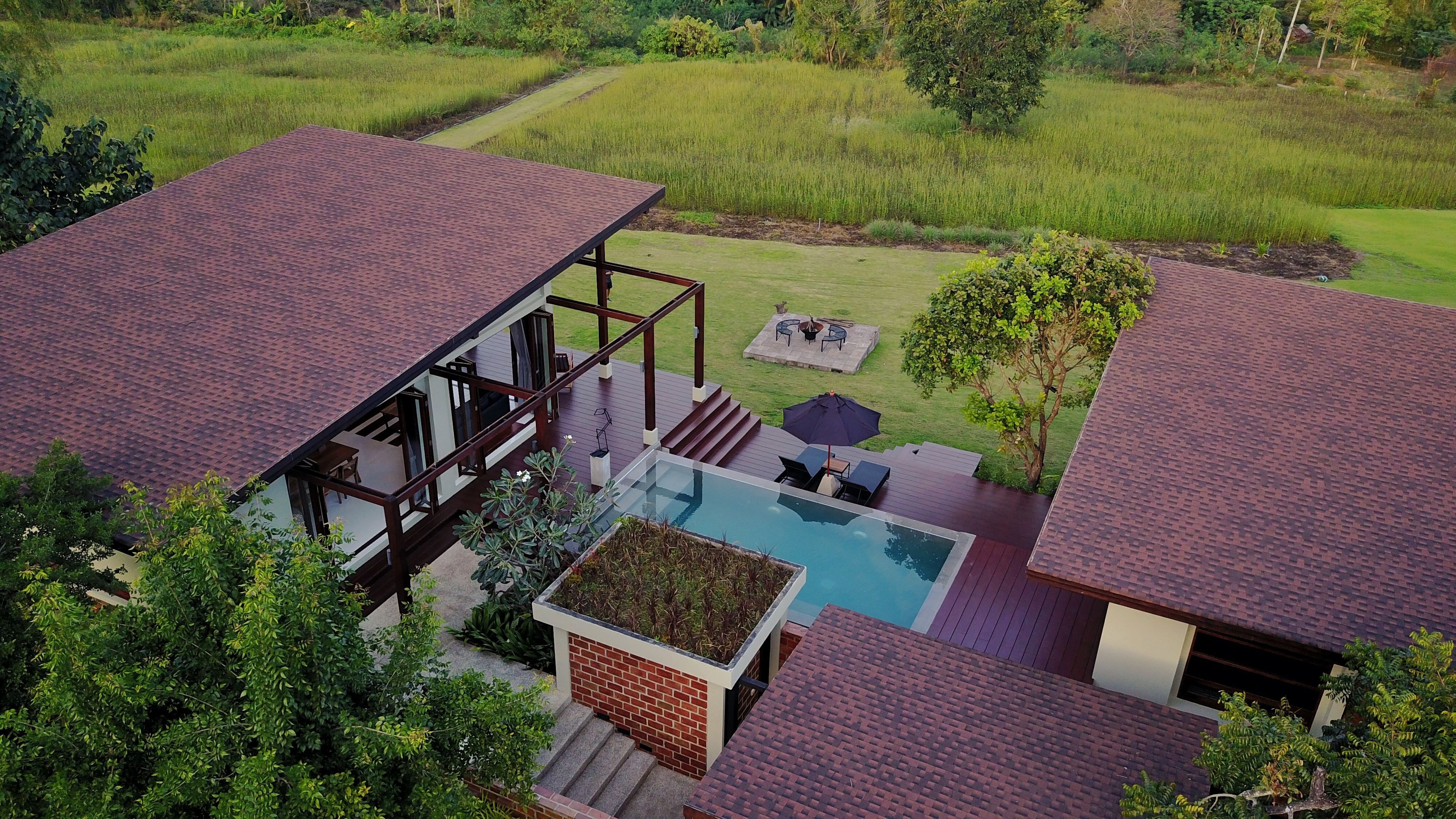 A modern house with a swimming pool, a deck, and a view of surrounding fields.