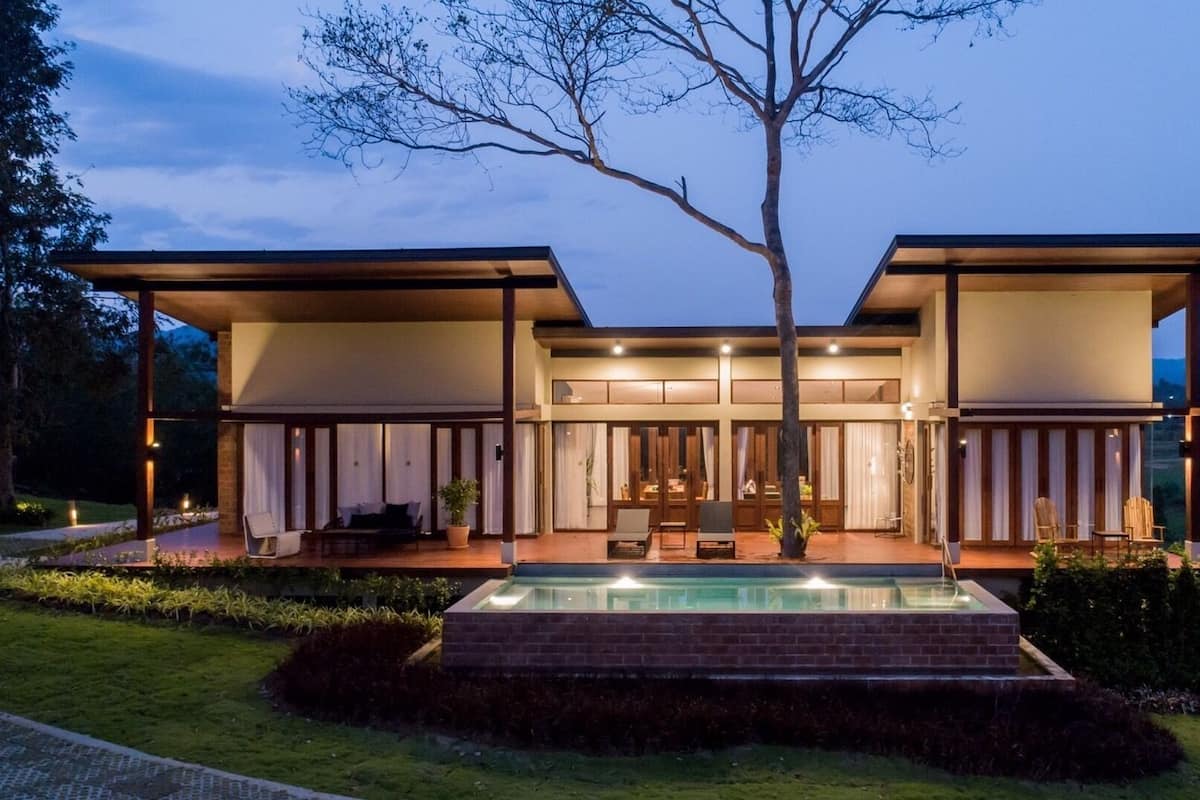 A modern two-story house with a swimming pool in the front.