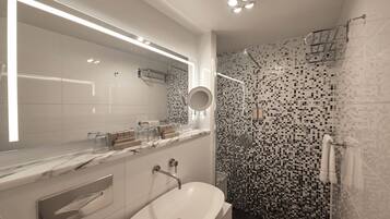 Un baño moderno con un espejo grande, encimera de mármol, lavabo blanco y ducha con mosaicos.