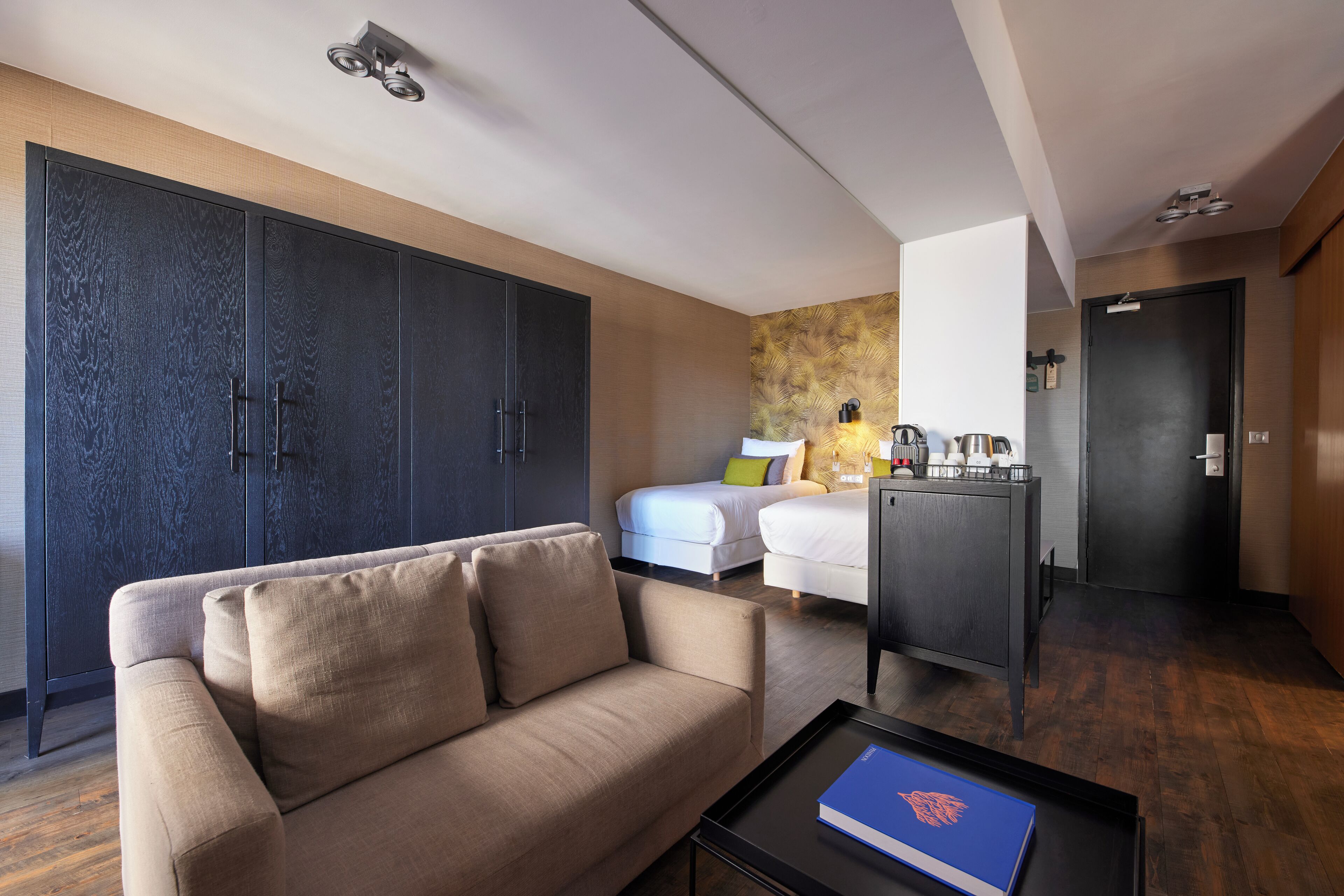 Hotellihuone, jossa on sohva, sänky, työpöytä ja vaatekaappi.