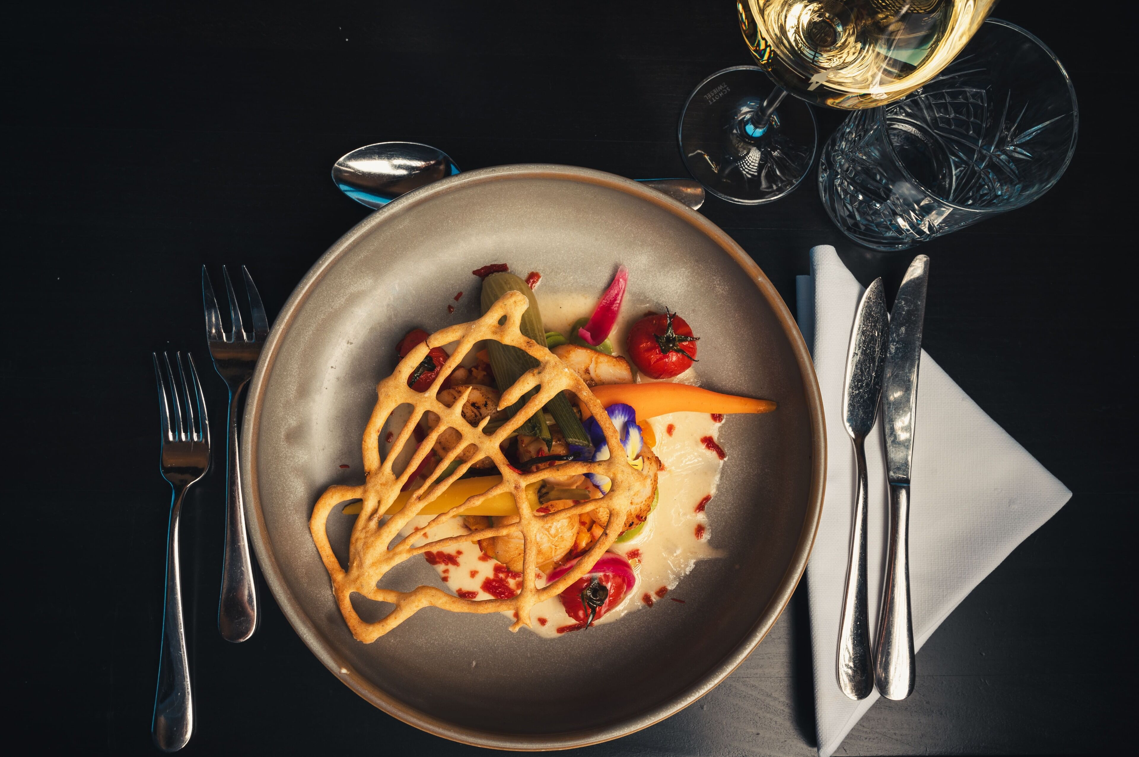 A plate of food with a fork and knife on a dark table.