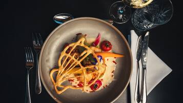 A plate of food with a fork and knife on a dark table.