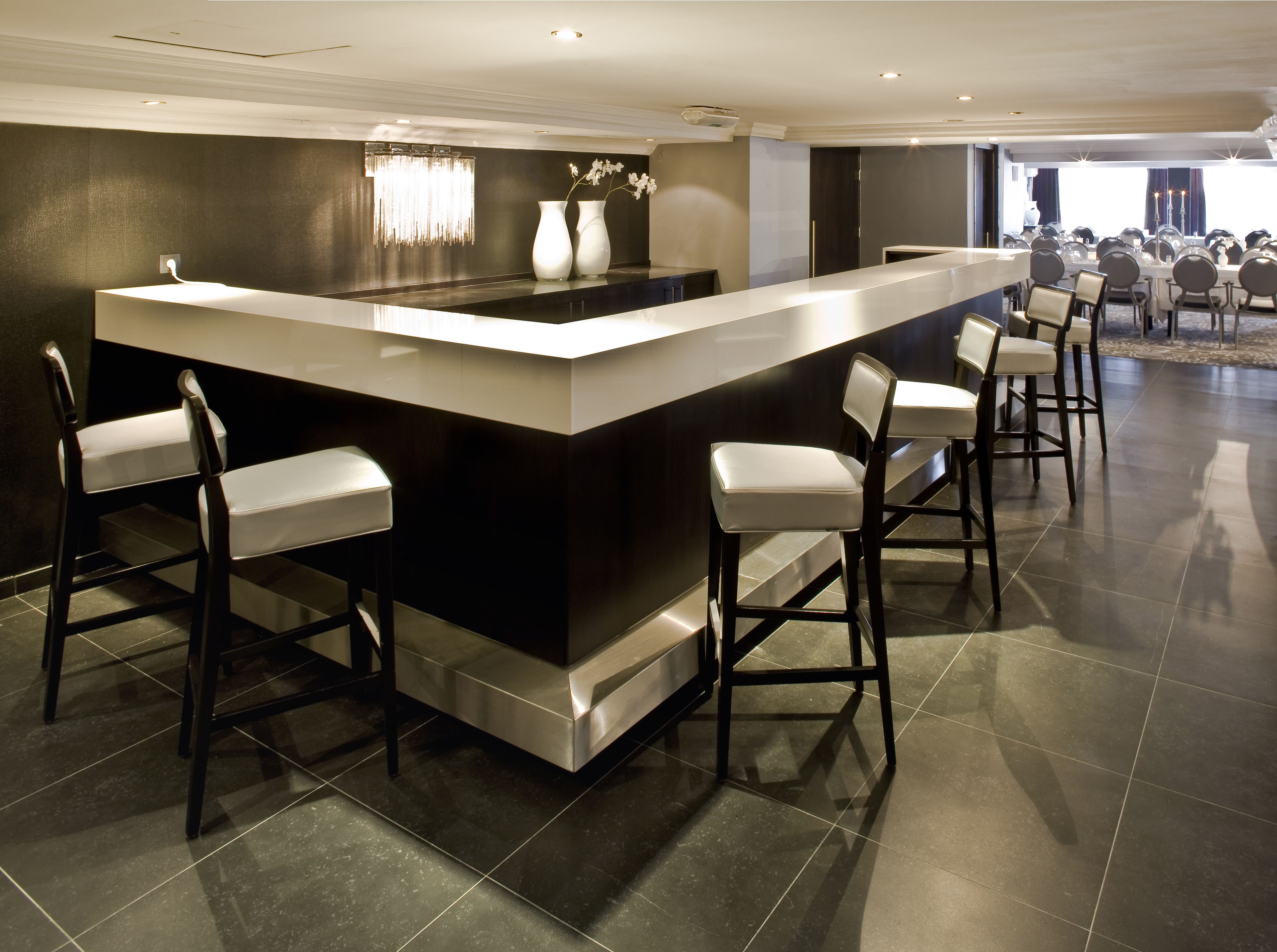 A modern bar area with a central island, bar stools, and a seating area with tables and chairs.