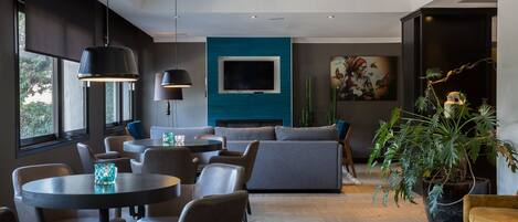 A modern living room with a large TV, comfortable seating, and a potted plant.