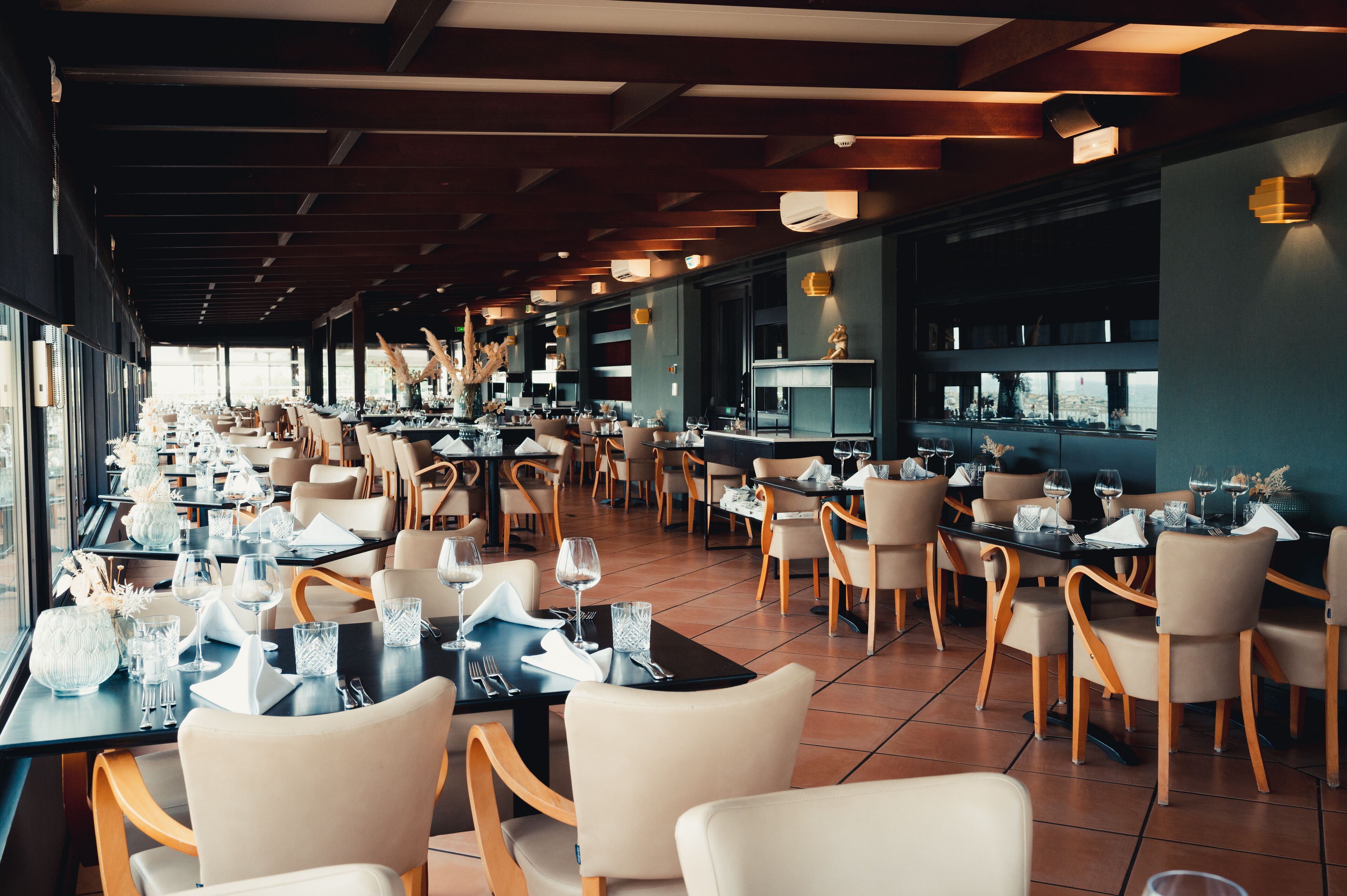 Un restaurant spacieux, doté de nombreuses tables et chaises, de grandes fenêtres et d’un aménagement intérieur moderne.