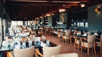 Un restaurante amplio con numerosas mesas y sillas, ventanas grandes y una decoración de interiores moderna.