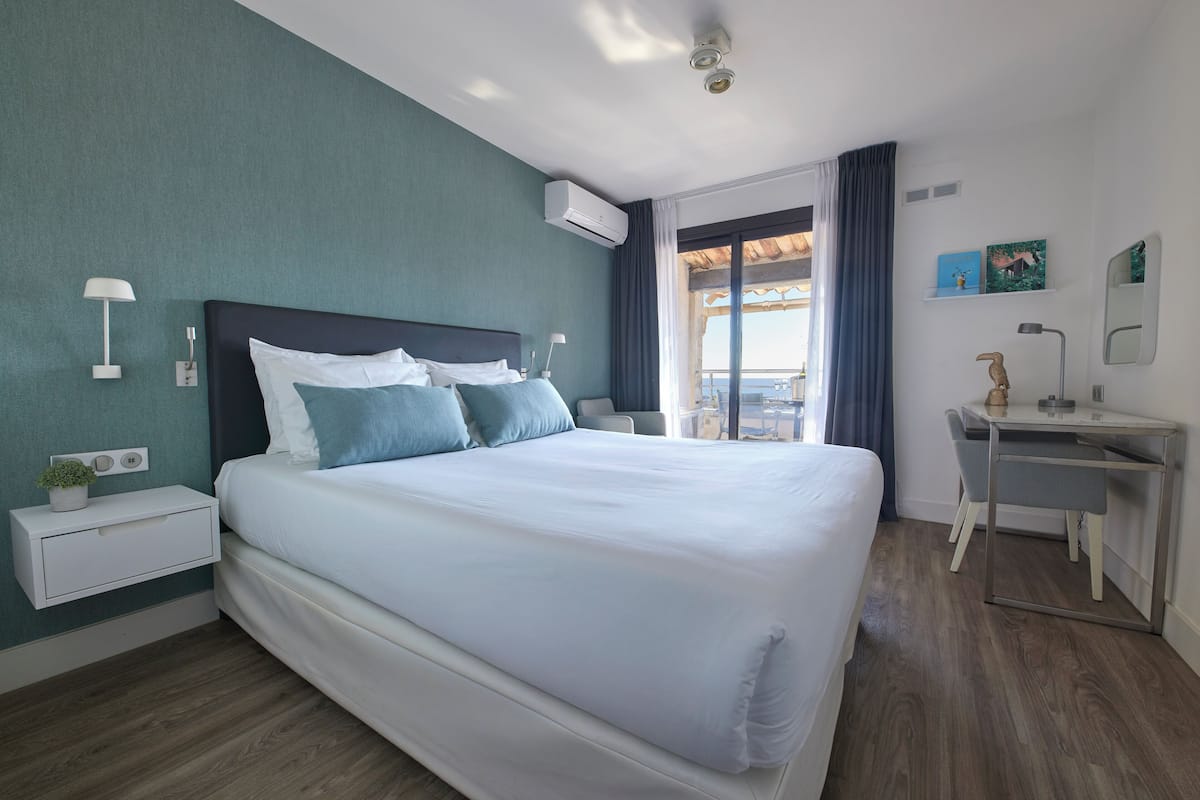 Une chambre d’hôtel moderne avec un grand lit, un bureau et une vue sur l’extérieur.