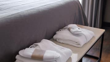 Una toalla blanca doblada con cuidado y un par de calcetines blancos sobre una mesa de madera en una habitación de hotel.