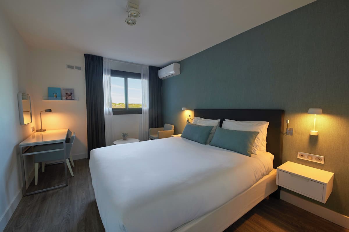 Une chambre d’hôtel avec un grand lit, des tables de chevet, un bureau et une chaise.