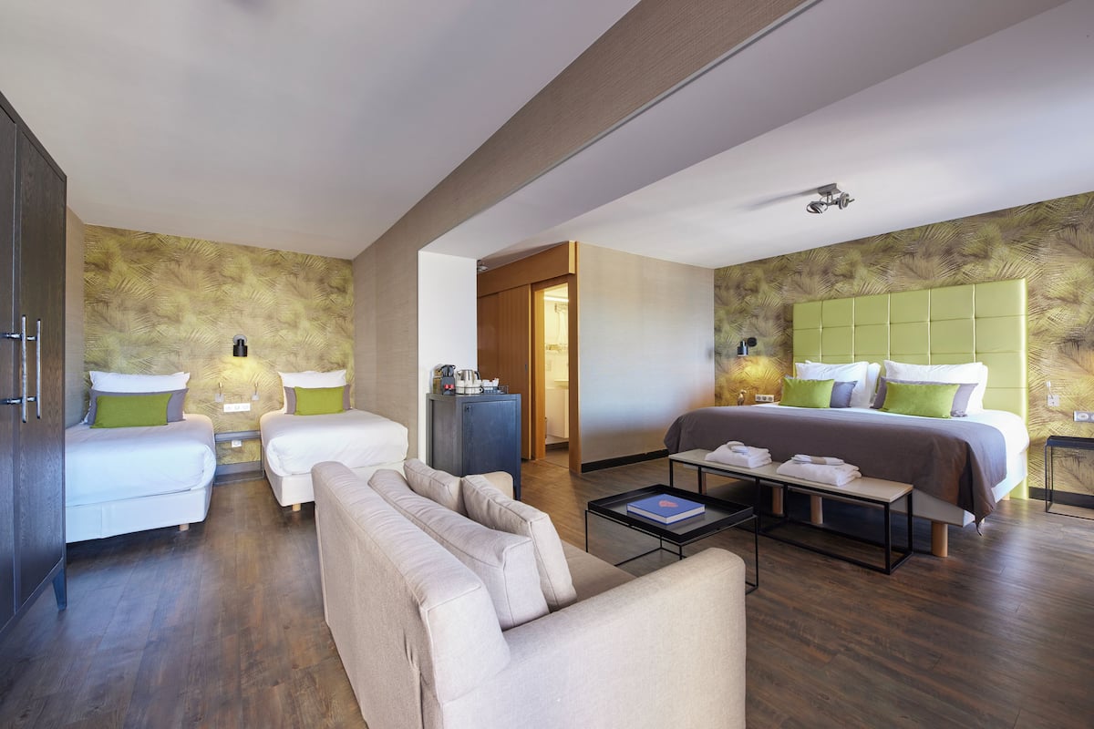 Une chambre d’hôtel moderne équipée de deux lits simples, d’un canapé, d’une table basse et d’un bureau.