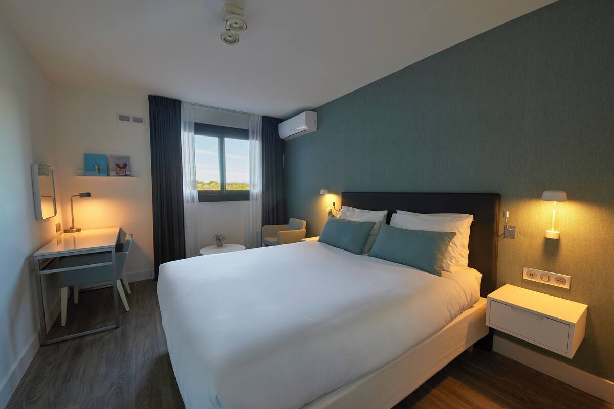 Une chambre d’hôtel avec un grand lit, des tables de chevet, un bureau et une chaise.