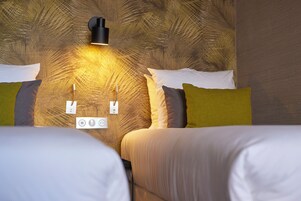 Habitación de hotel con dos camas, una lámpara en la pared y un enchufe.