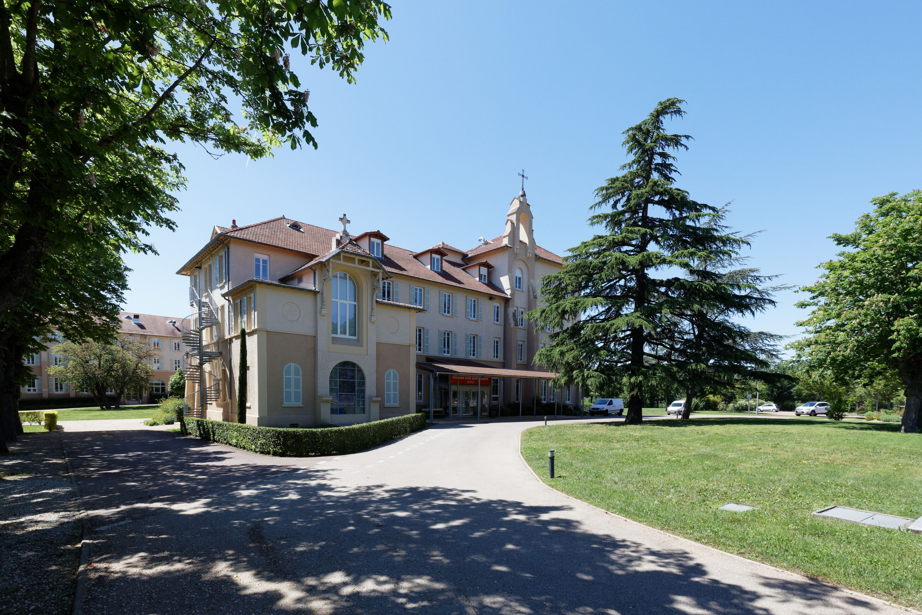A large, historic building with a central entrance, surrounded by a well-maintained lawn and trees.