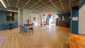 A spacious indoor area with a wooden herringbone floor, tables, chairs, and a large wooden cabinet. - Domaine Lyon Saint Joseph (Francheville)