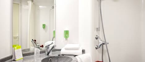 A bathroom with a granite sink, a mirror, a handheld showerhead, and a towel rack.