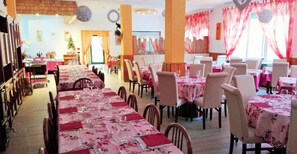 A dining area with multiple tables set for guests, featuring a consistent floral tablecloth theme. - Hotel Neni (Brentonico)