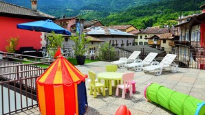 Un patio con mobiliario exterior, una zona de juegos pequeña y vistas a montañas.
