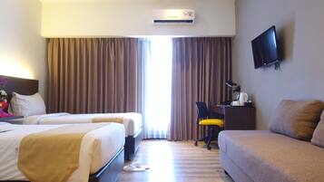Habitación de hotel con dos camas, un escritorio con silla, televisor de pantalla plana y aire acondicionado.