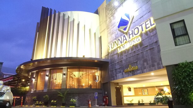 A modern hotel with a curved facade, a prominent sign reading "YUNNA HOTEL LAMPUNG," and a well-lit entrance. - Yunna Hotel (Bandar Lampung)