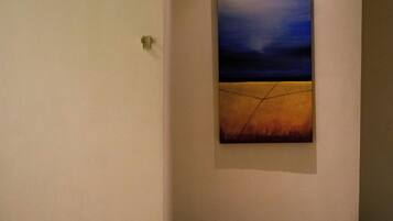 Un couloir avec un tableau accroché au mur et un plancher en bois.
