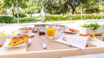 Ein Frühstückstisch mit Kuchen, Orangensaft und verschiedenen Früchten und Gebäck.