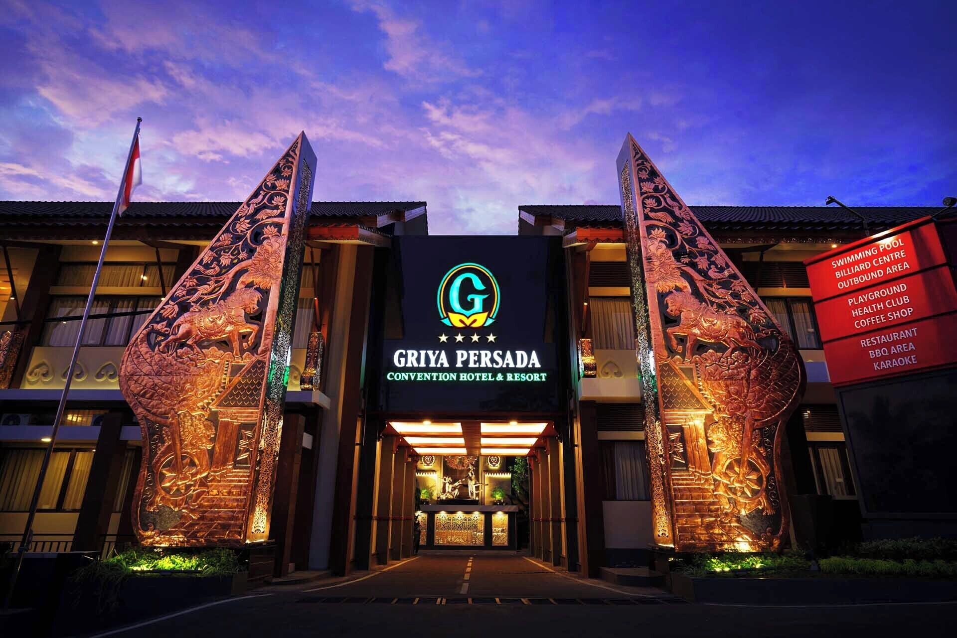 The entrance to Gria Persada, a hotel with a traditional architectural design and a signboard listing amenities like a swimming pool, health club, and karaoke.