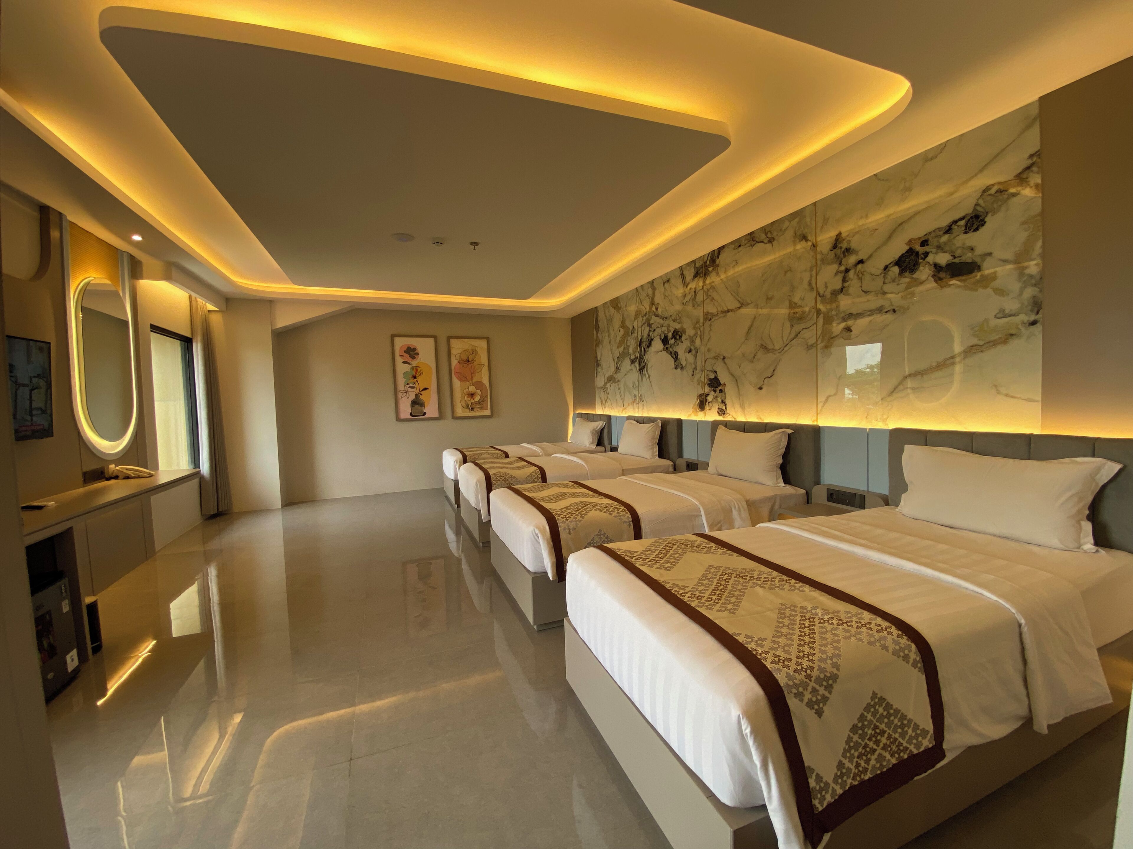 Una habitación de hotel moderna con tres camas, un espejo grande, obras de arte en las paredes y un elemento decorativo en la pared que imita el mármol.