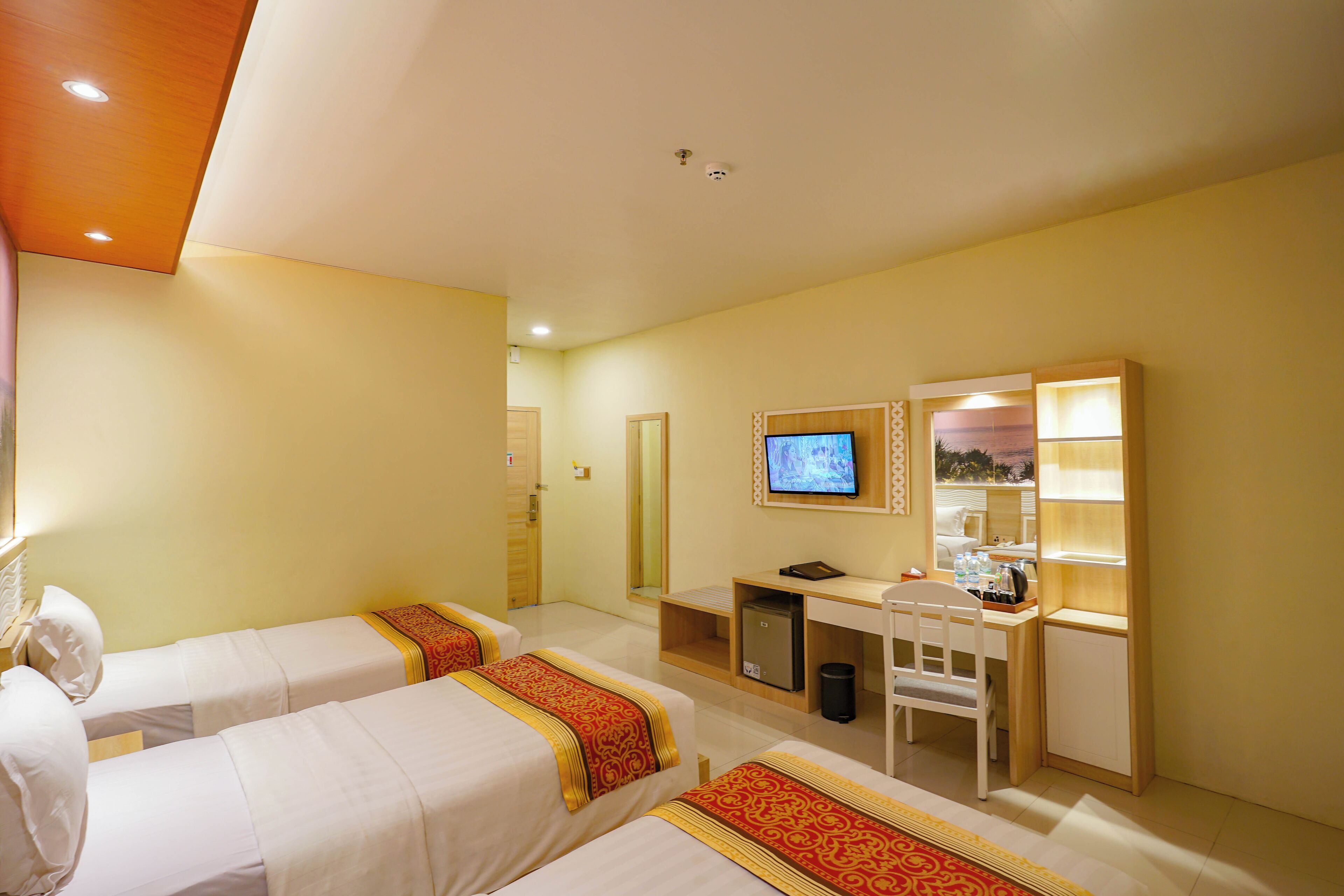 Ein Hotelzimmer mit zwei Betten, einem Schreibtisch, einem Fernseher und einer kleinen Mülltonne.