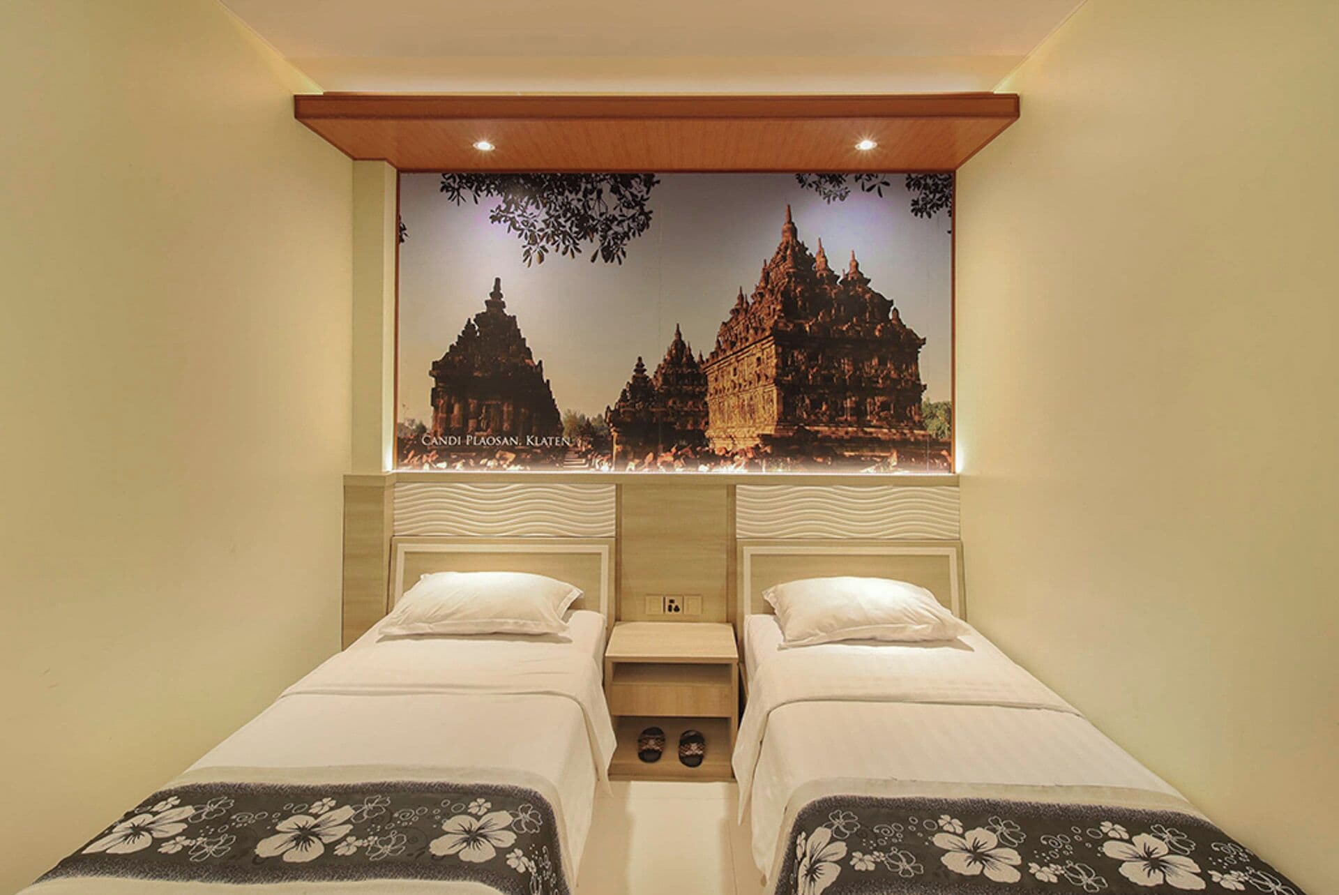 Une chambre d’hôtel avec deux lits, une fresque représentant un temple et un plafond en bois.