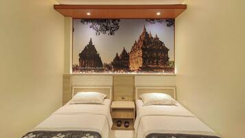 Une chambre d’hôtel avec deux lits, une fresque représentant un temple et un plafond en bois.