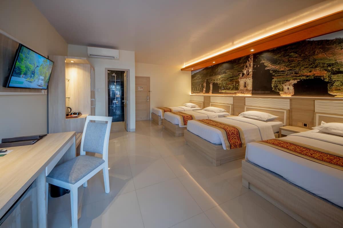 A hotel room with a desk, two beds, a TV, and a mural on the wall.