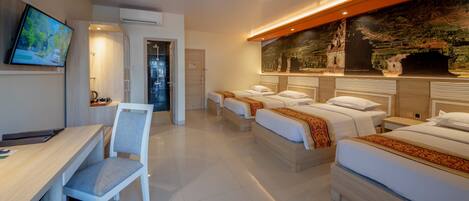 A hotel room with a desk, two beds, a TV, and a mural on the wall.