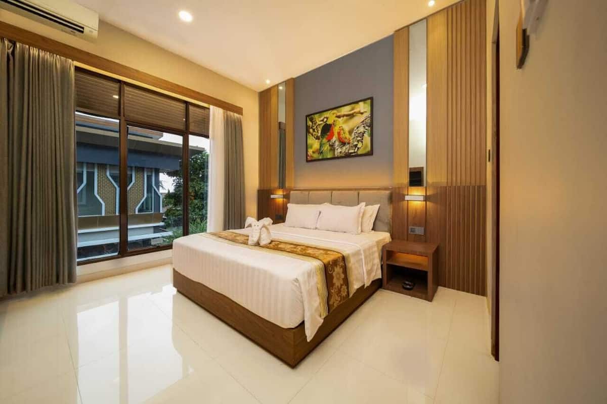 A modern hotel room with a large bed, a painting on the wall, and a view through the window.
