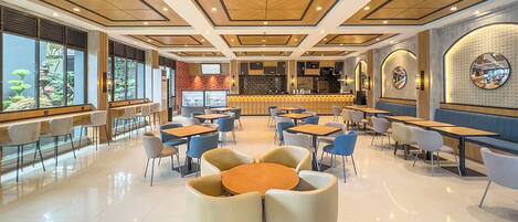 A modern restaurant with a bar area, round tables, and chairs.